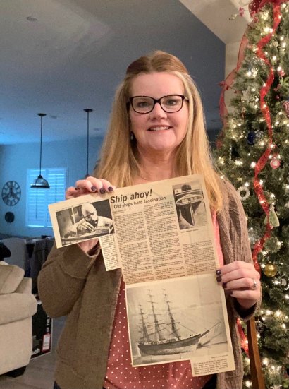 Cheryl Symonds with one of several newspaper articles written about her father's hobby, building intricate model ships. 